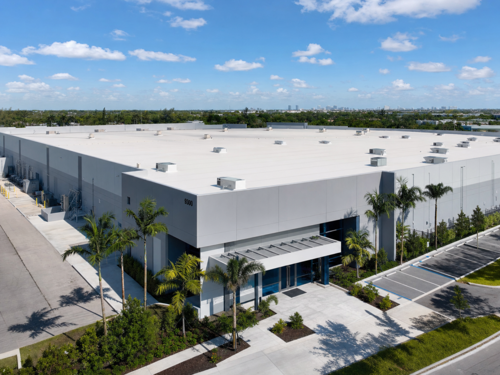 Drone view of a massive, clean white TPO roof on a modern industrial warehouse building.