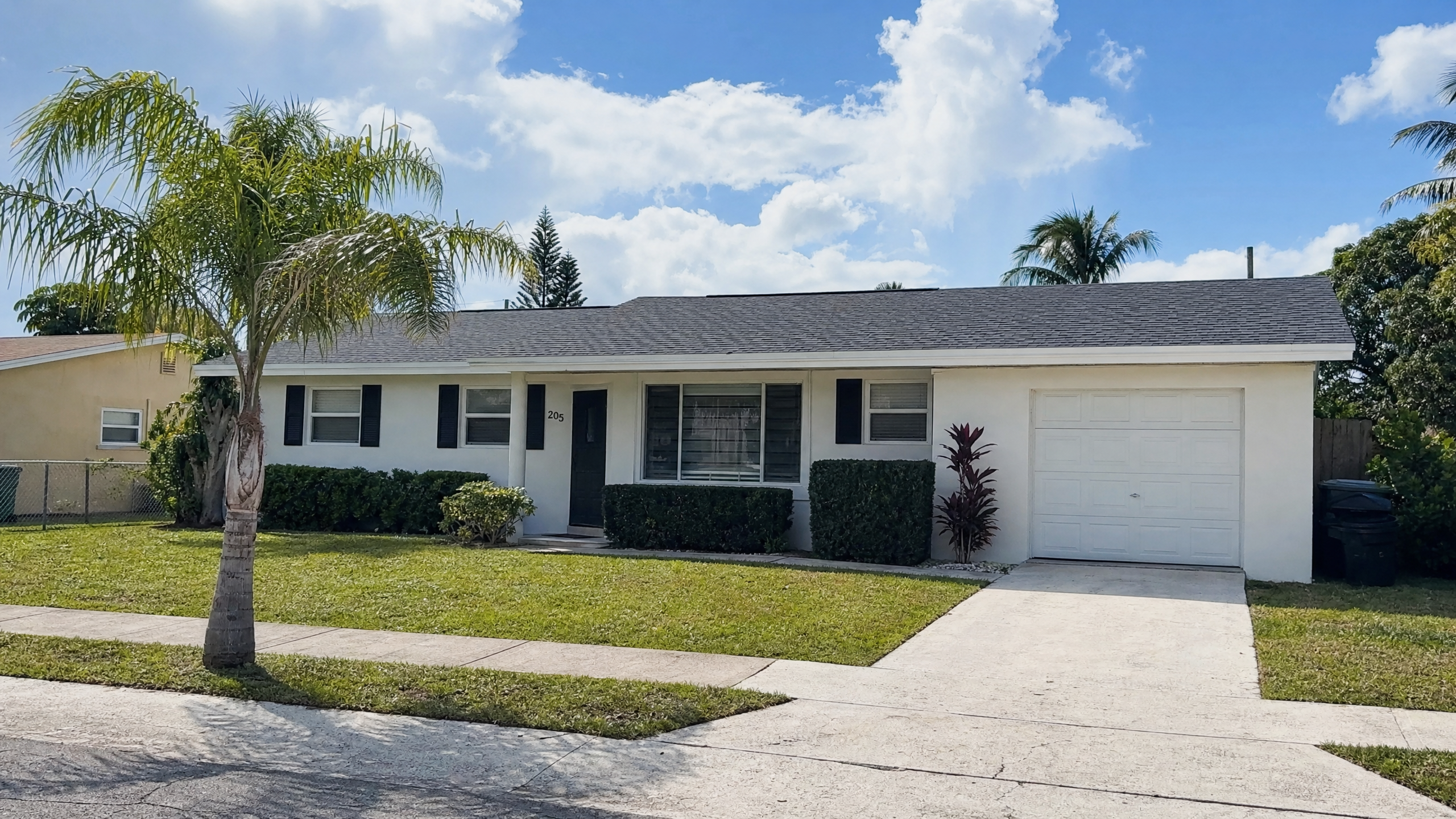 A newly installed architectural shingle roof on a modest 1960s-70s ranch-style home in Mangonia Park, Florida.