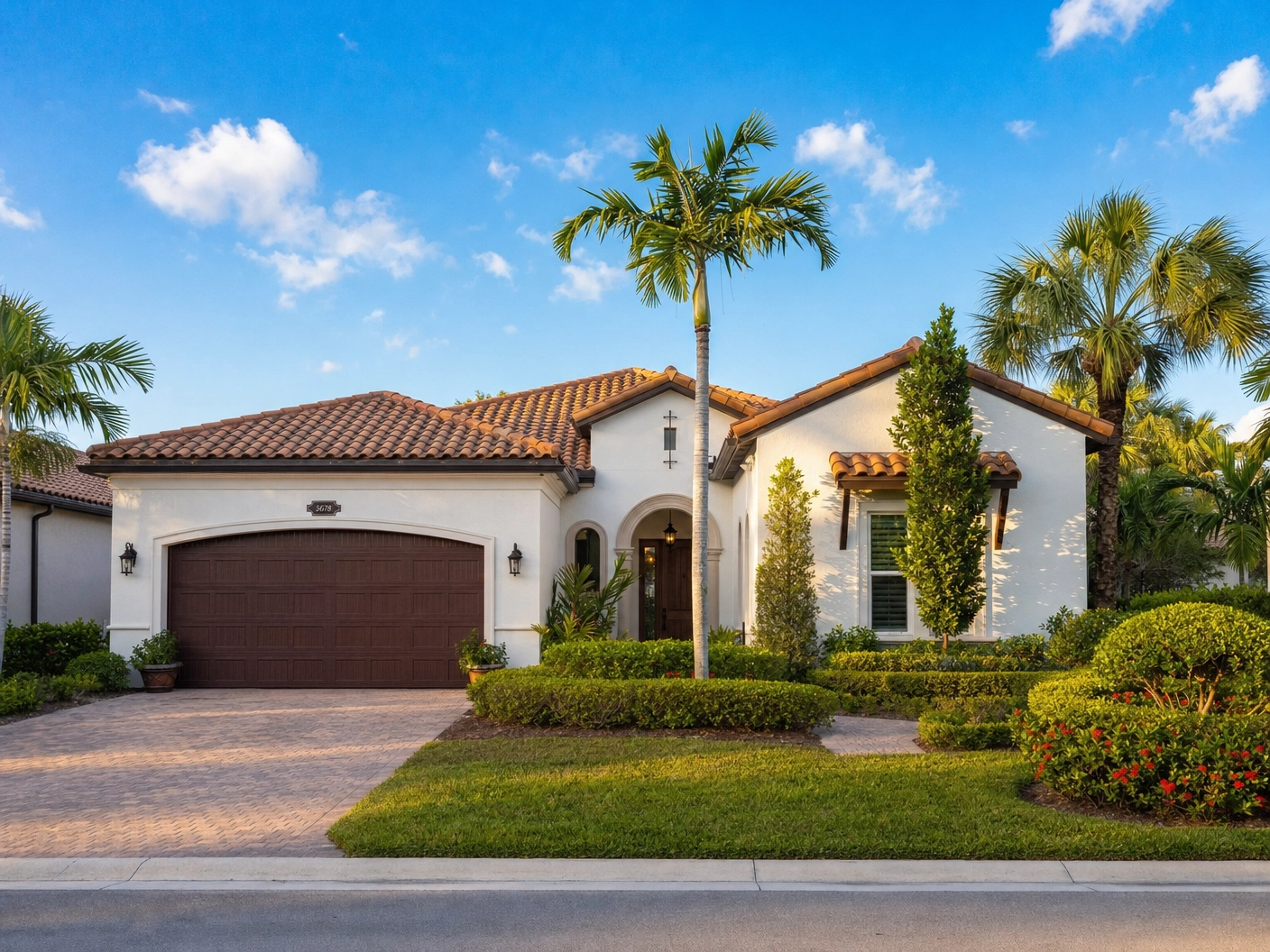 A luxury white Mediterranean-style home in South Florida featuring a new brown barrel tile roof and professional landscaping.